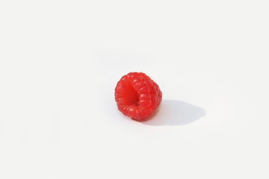 Single raspberry against white background