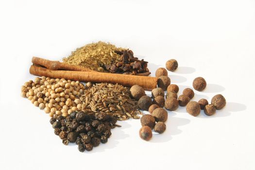 Various spices in piles against white background