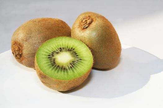 Three kiwi fruit against white background with a shadow