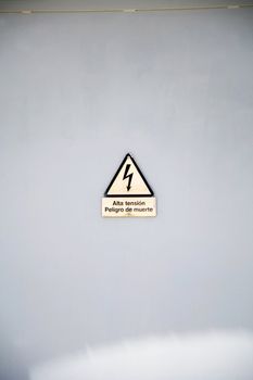 danger high tension sign on a grey wall