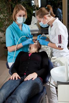 Woman patient being helped by a female dentist and her assistent