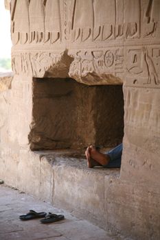 feet appear inside a hole in a wall of egyptian temple