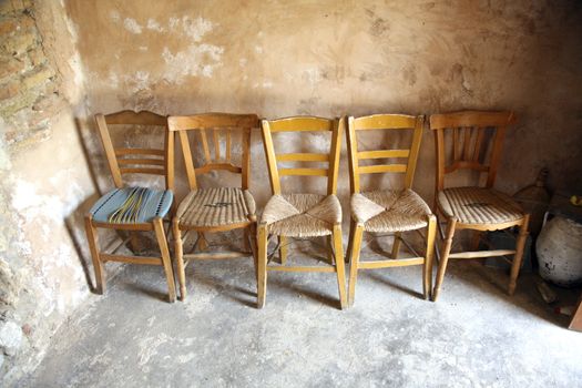 five old wooden chairs inside a chapel in crete