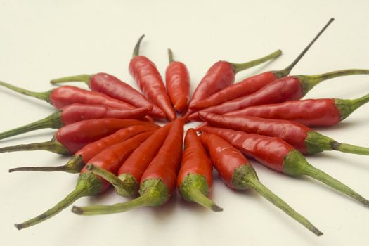 A pile of small red chili peppers arranged and isolated against a white background