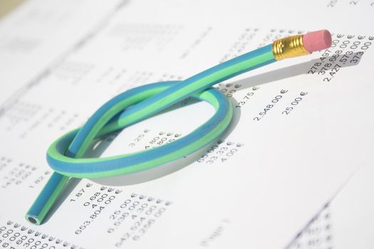 A green and blue striped rubber pencil tied in knot sitting on accounting printout