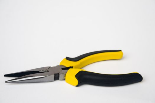 Yellow and black handled needle nose pliers against a white background