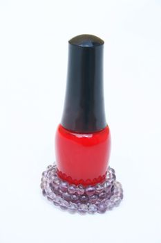 A bottle of red fingernail polish with purple beaded necklace wrapped around