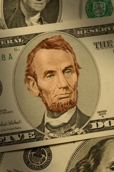 Close-up of Abraham Lincoln on the $5 bill, dramatically lit and hand-colored.