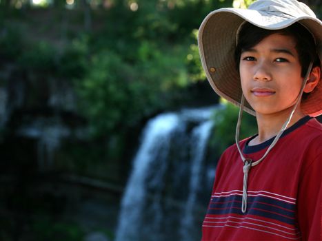 Young boy standing nect to water fall