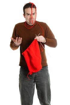 A young man having troubles with his knitting, isolated against a white background