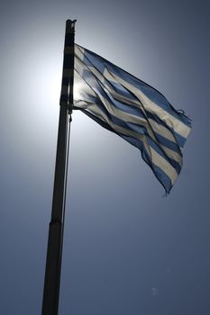 greek flag flying against the sun in crete