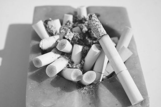 Close-up of square ashtray full of burnt cigarettes