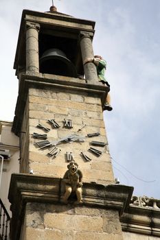 spanish bell tower with a statue screaming and a puppet hitting bell