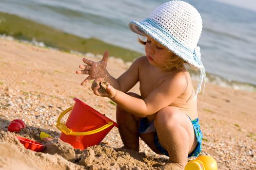 little girl in the bonnet plaing with sand, childhood