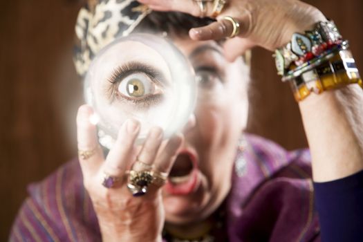 Female gypsy fortune teller holding a crystal ball to her eye