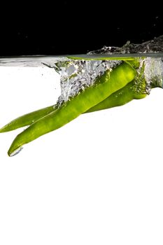 some green chilli thrown in water with black and white background