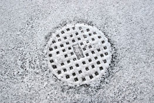 a snow covered manhole cover on the road surface