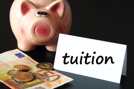 education tuition concept with piggy bank on black background