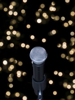 A microphone alone on stage full of out of focus lights.