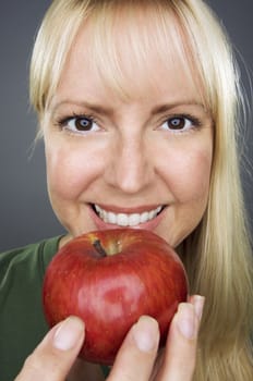 Beautiful Woman With Apple Against A Grey Background