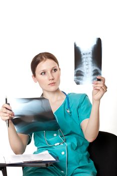 Female doctor in the green uniform looking at the xray pictures