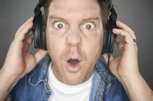 Shocked Man Wearing Headphones against a grey background.