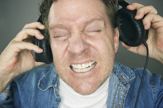 Shocked Man Desperately Trying To Take Off His Headphones.