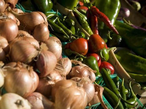 Onions, red peppers and green peppers in blue baskets.