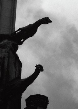Silhouette of rainspout gargoyles on side of cathedral against stormy sky