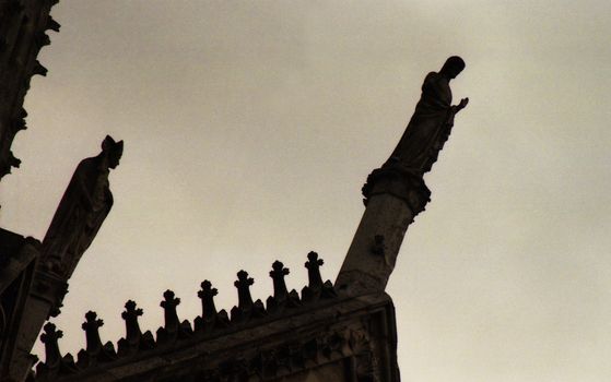 Silhouette of statues on top of roof overhang of cathedral