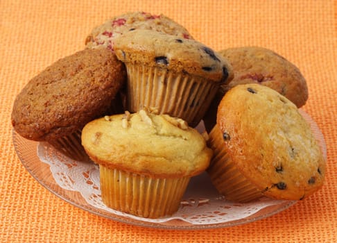 variety of muffins on a plate, orange tablecloth