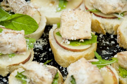 closeup on freshly made salmon canapes with rucola, pear and parmesan