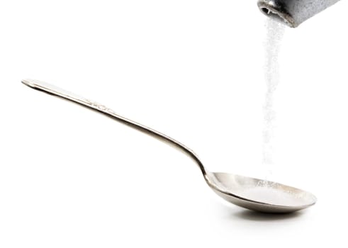pouring sugar in a silver spoon, isolated on white