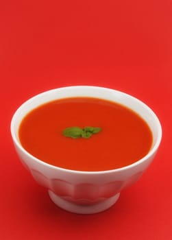 tomato soup in white bowl, red background