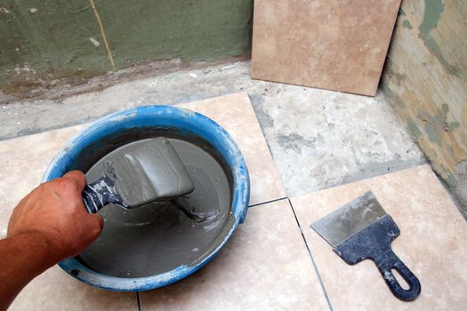 construction worker laying ceramics bricks on floor