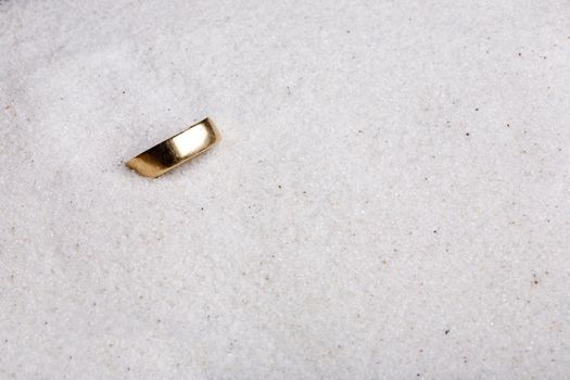 A lost ring hiding in soft white sand.