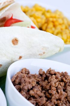 A macro of a prepared taco with ingredients in th background