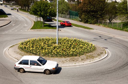 A traffic circle with a white car going around