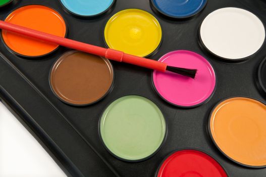 Close up capturing a paint brush placed on a section of a child's paint set.