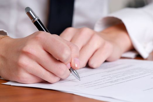 person's hand signing an important document