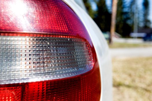 A red and white rear car light with sun reflection