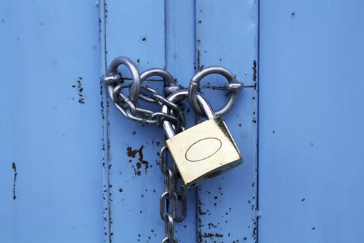 Padlock with chain on blue metal door
