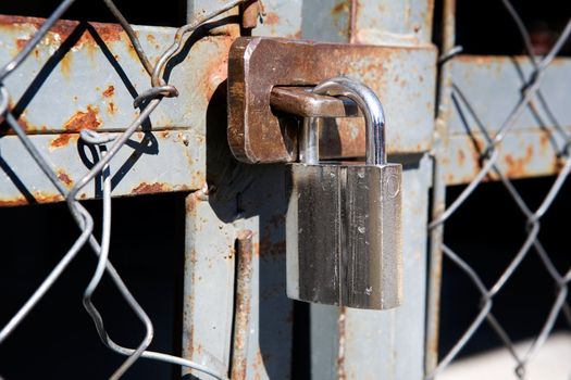 A large padlock on a wire mesh gate