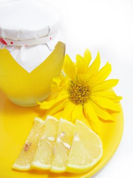 Jar of honey with lemon and yellow flower