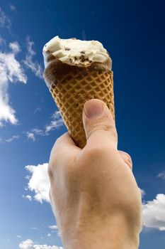 An ice cream cone with a bite isolated against a deep blue sky