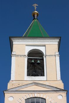 The top of bell tower over sky-blue background
