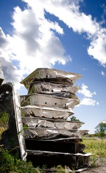 A stack of tinfoil disposable barbcues against a blue summer sky