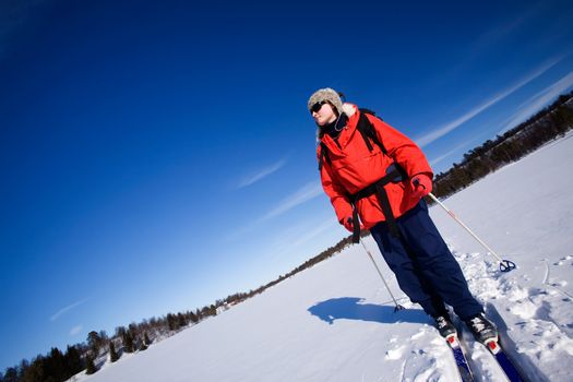 A woman cross country skiing across a frozen lake