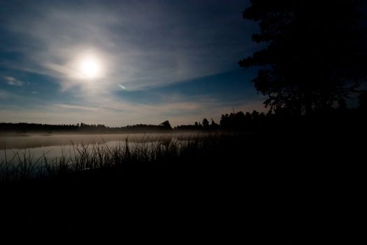 A landscape of a lake at night with the moon