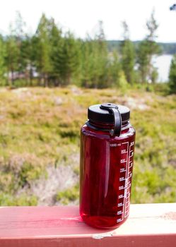 A red water bottle outdoors in nature